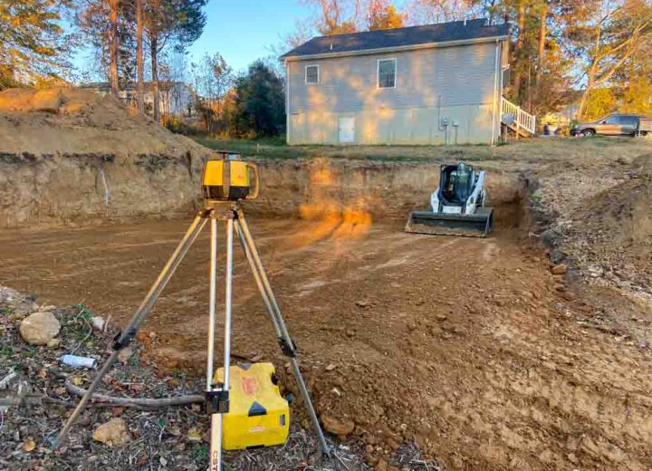Theodolite, a levelling instrument in the foreground and a crawler loader on construction site leveling ground